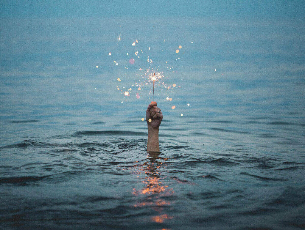mano con scintilla fuoco d'artificio fuoriuscire dall'acqua