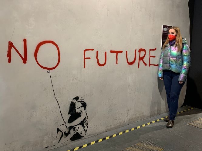 Cristina Bertolino vicino all'opera: No Future esposta alla mostra The World of Banksy Torino