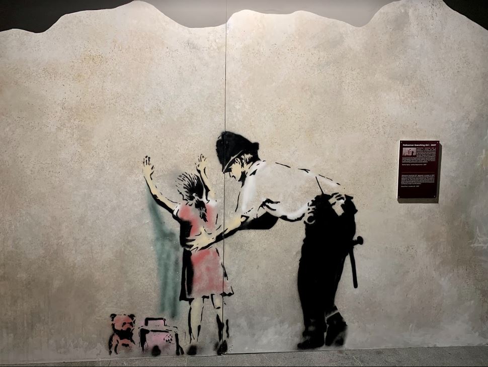 Policeman Searching Girl in The World of Banksy